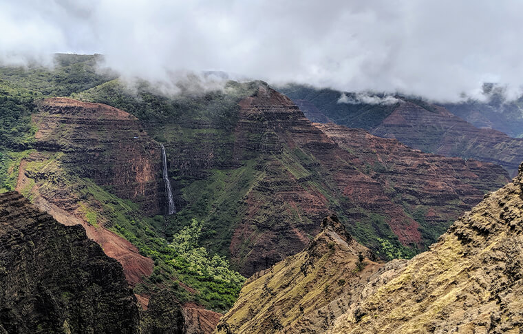 Grey and white clouds covering the tops of an amazing canyon